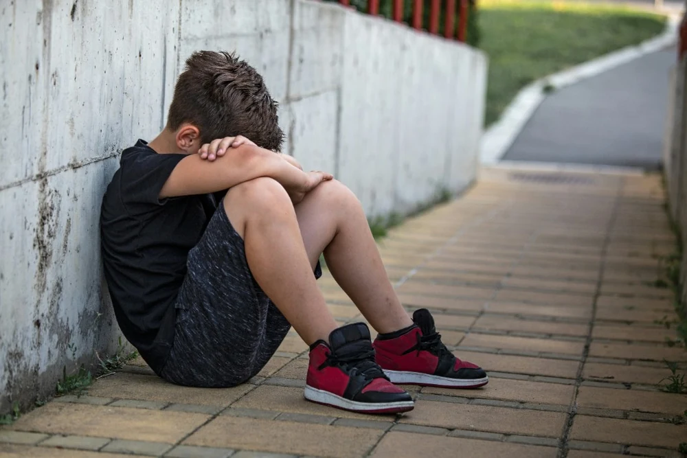 Child sitting with head down, shut down at transition