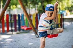 Child playing alone on a swing at a playground