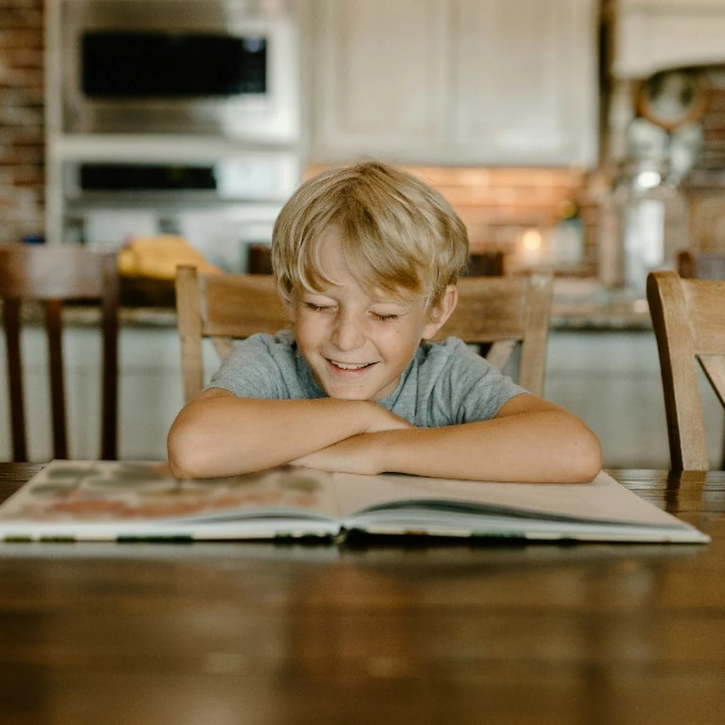 A child reading a workbook at the kitchen table
