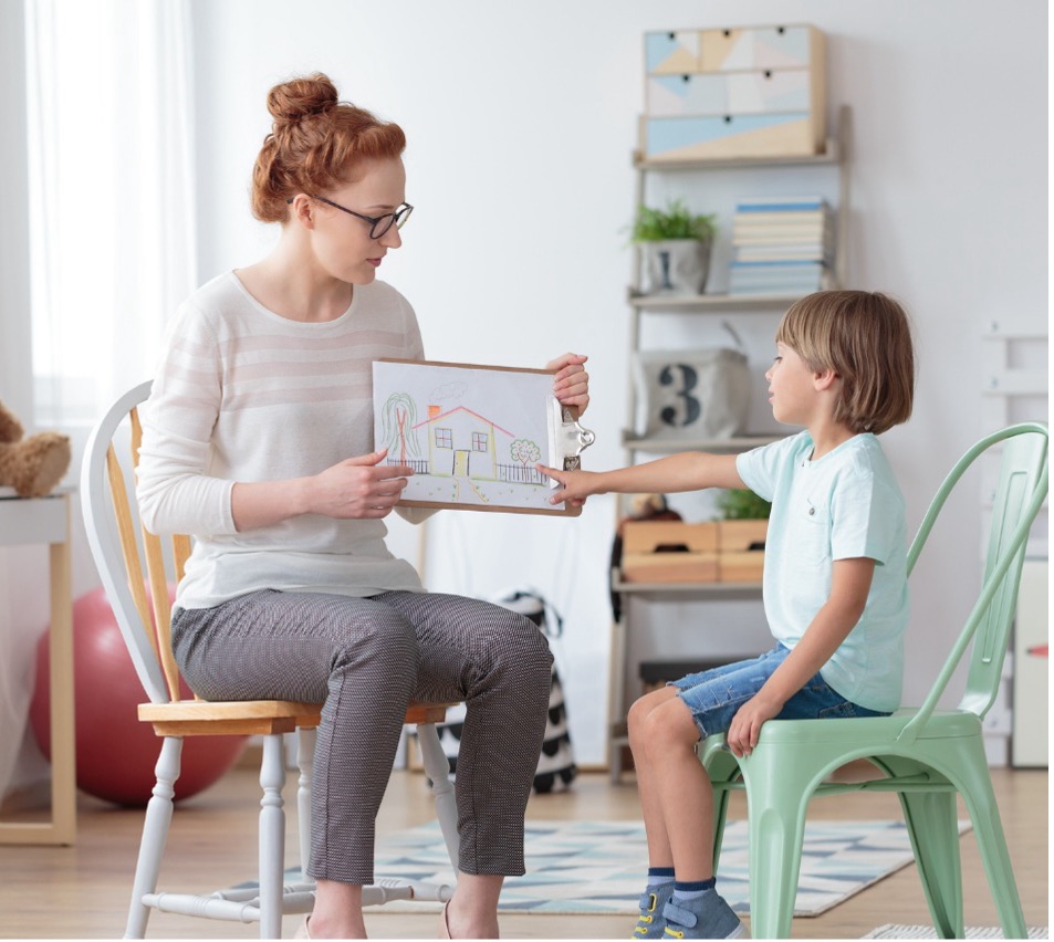 A therapist showing a child a drawing during a clinical session